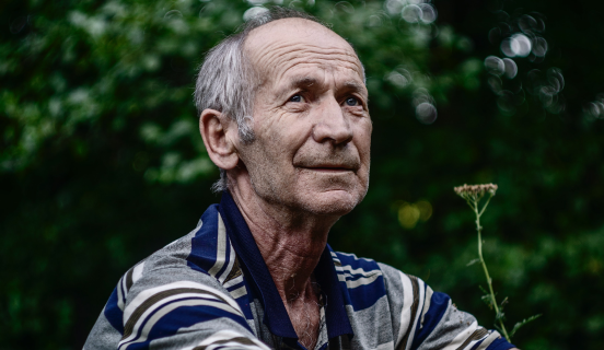 older man looking up at trees