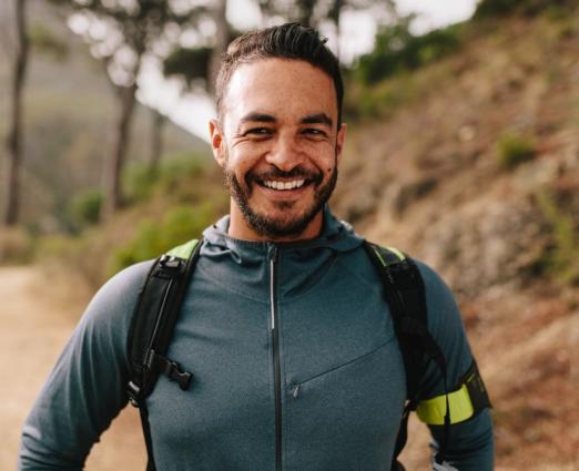 man hiking on trail smiling 