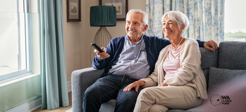 Two older adults sitting at home on couch with television remote