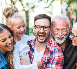 smiling family including grandma, grandpa mother, father, and child close together hugging and smiling